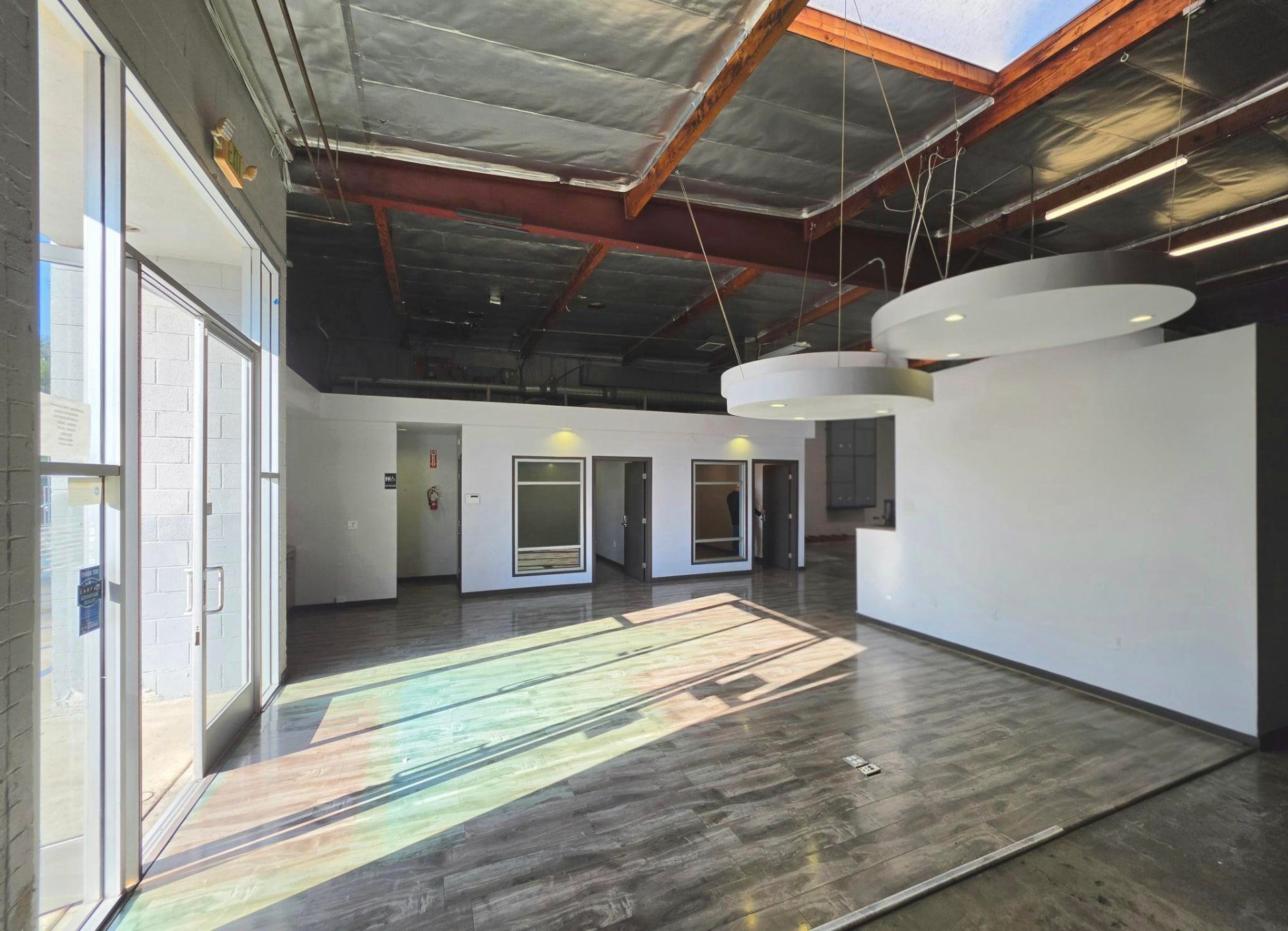 Interior entry area with glazed storefront, wood floors and suspended lighting
